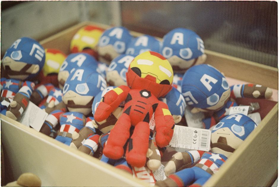 From above of crop unrecognizable person showing superhero toy packed in transparent plastic box