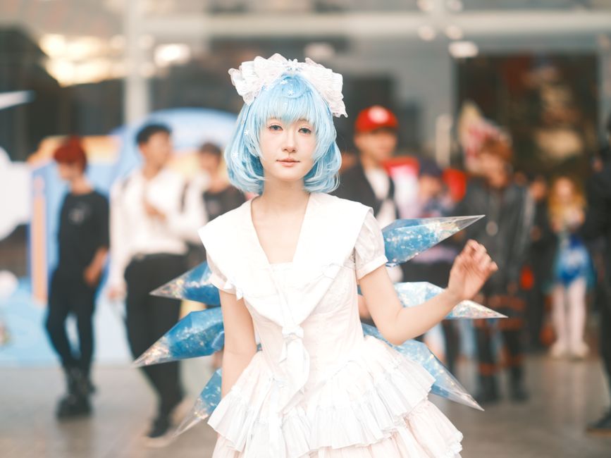 Charming cosplay featuring a fantasy character with long blonde hair and pink outfit inside a hallway.
