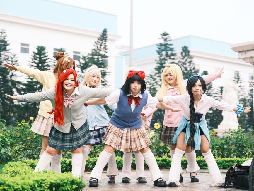 A lively group of cosplayers posing outdoors, showcasing colorful costumes in a cheerful setting.